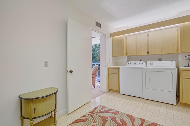 clothes washing area with cabinets, washer and dryer, and a textured ceiling