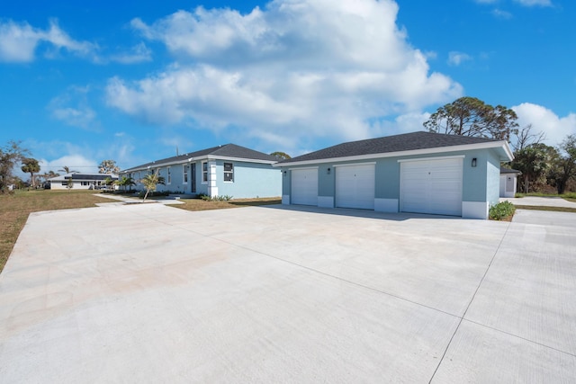 view of front of house featuring stucco siding, an outbuilding, and concrete driveway