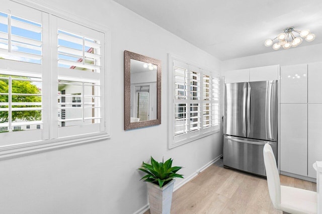 kitchen with white cabinets, stove, a chandelier, and stainless steel refrigerator