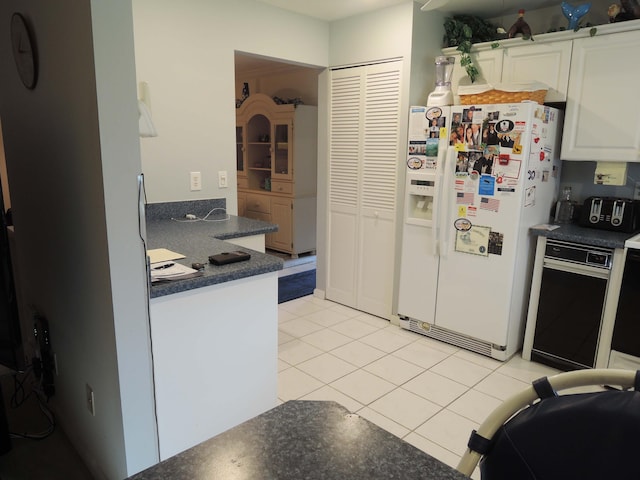 kitchen with white cabinets, light tile patterned floors, and white refrigerator with ice dispenser