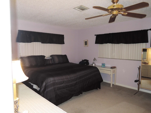 carpeted bedroom featuring a textured ceiling, ensuite bathroom, and ceiling fan