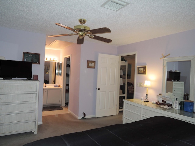 bedroom with ceiling fan, a textured ceiling, connected bathroom, and carpet