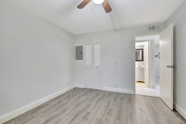 unfurnished bedroom with electric panel, ceiling fan, a closet, and light wood-type flooring