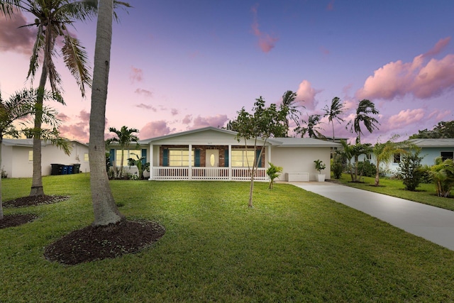 ranch-style house featuring a yard, covered porch, and a garage