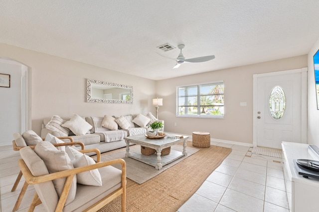 living room with a textured ceiling, ceiling fan, and light tile patterned flooring