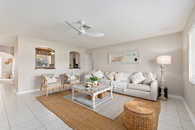 tiled living room with ceiling fan and a textured ceiling