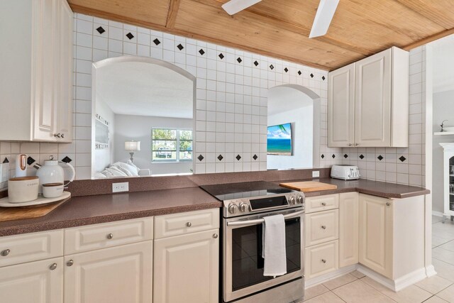 kitchen featuring backsplash, electric stove, white cabinetry, and light tile patterned floors