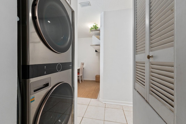 laundry area featuring light tile patterned flooring and stacked washer / drying machine