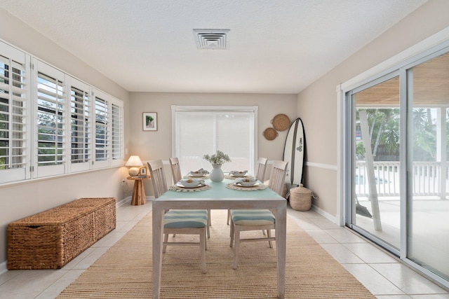 tiled dining room featuring a healthy amount of sunlight and a textured ceiling