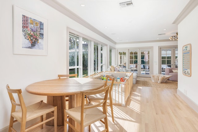 dining area featuring a healthy amount of sunlight, light wood-type flooring, french doors, and ornamental molding