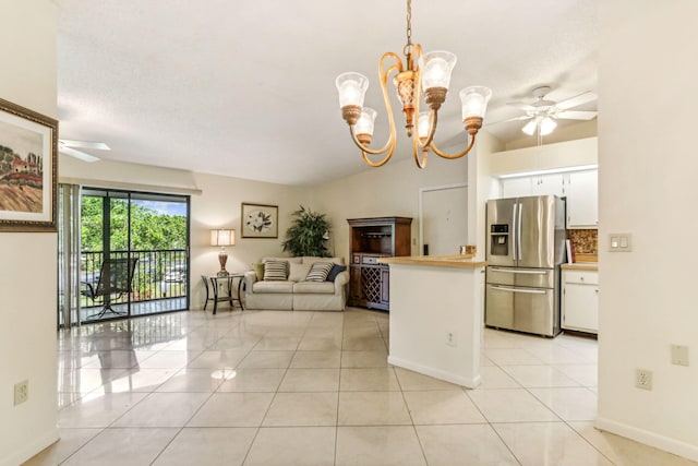 kitchen featuring pendant lighting, lofted ceiling, stainless steel refrigerator with ice dispenser, light tile patterned flooring, and white cabinetry