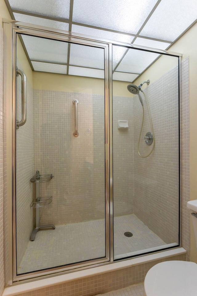 bathroom with a shower with door and toilet