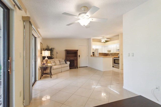 tiled living room with ceiling fan, a healthy amount of sunlight, and a textured ceiling