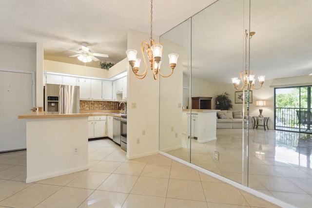 kitchen featuring stainless steel appliances, sink, light tile patterned floors, decorative light fixtures, and white cabinetry