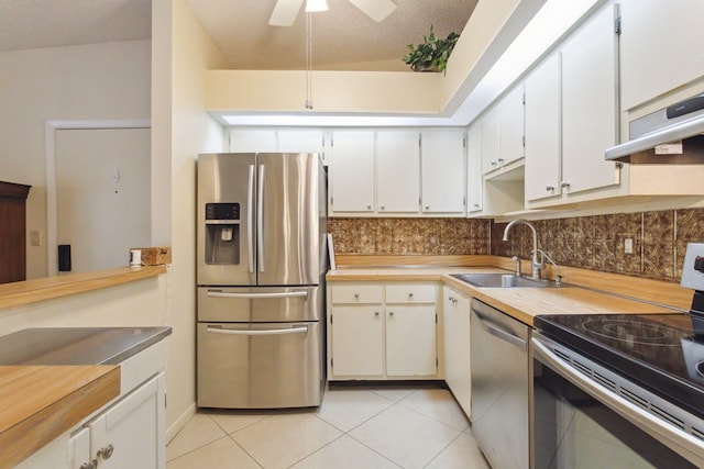 kitchen with sink, light tile patterned floors, a textured ceiling, white cabinetry, and stainless steel appliances