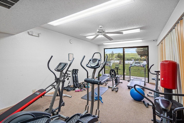 exercise area featuring ceiling fan and a textured ceiling