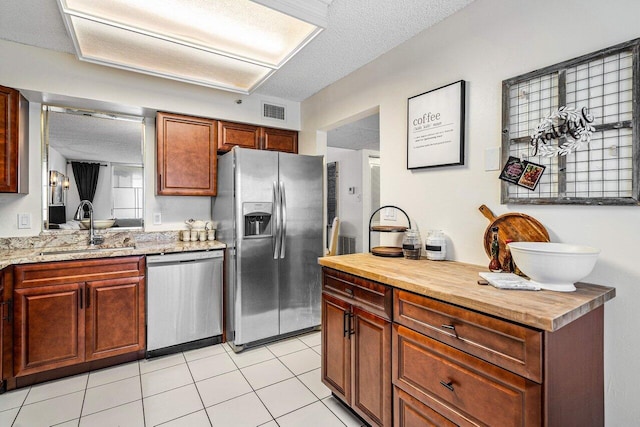 kitchen with butcher block countertops, sink, stainless steel appliances, and a textured ceiling