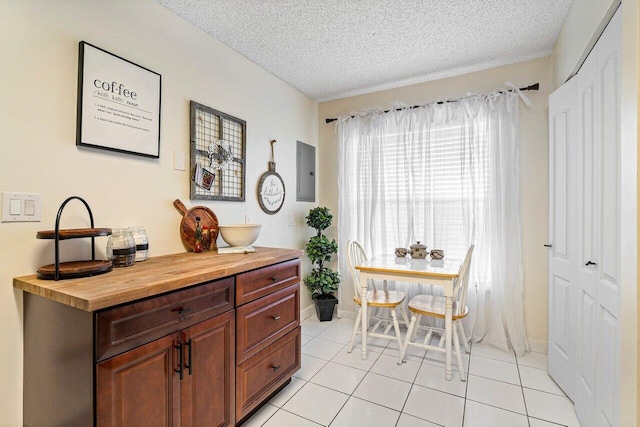 dining space with light tile patterned floors, a textured ceiling, and electric panel