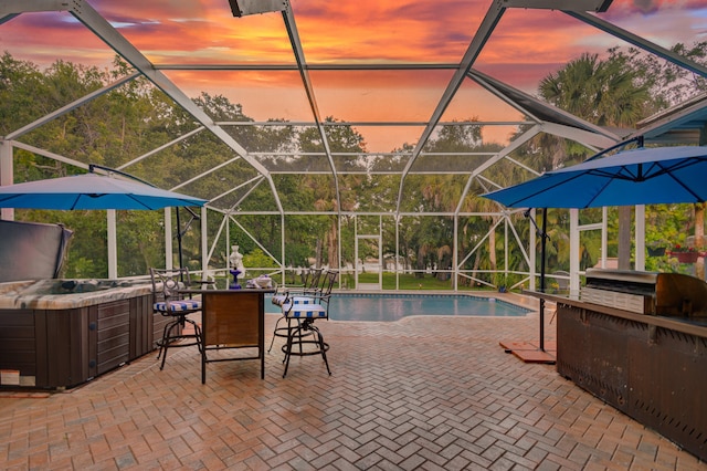 pool at dusk with area for grilling, a lanai, an outdoor bar, and a patio