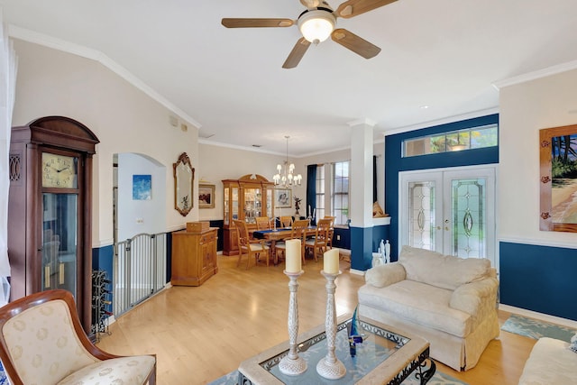 living room with light wood-type flooring, french doors, ornamental molding, and ceiling fan with notable chandelier