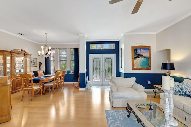 living room featuring ornamental molding, ceiling fan with notable chandelier, and light hardwood / wood-style flooring