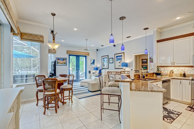 kitchen with dishwasher, kitchen peninsula, sink, a kitchen breakfast bar, and decorative light fixtures