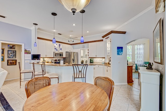 tiled dining room with ceiling fan and ornamental molding