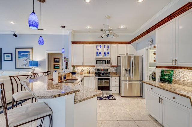 kitchen with sink, appliances with stainless steel finishes, ornamental molding, a kitchen bar, and hanging light fixtures