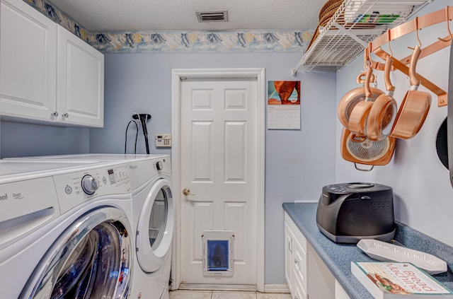 laundry room featuring a textured ceiling, separate washer and dryer, and cabinets