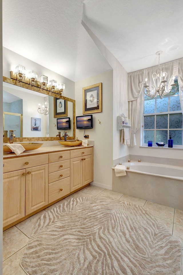 bathroom with tile patterned flooring, a textured ceiling, a chandelier, vanity, and a bath