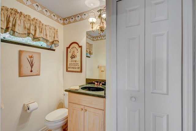 bathroom with toilet, vanity, and a textured ceiling