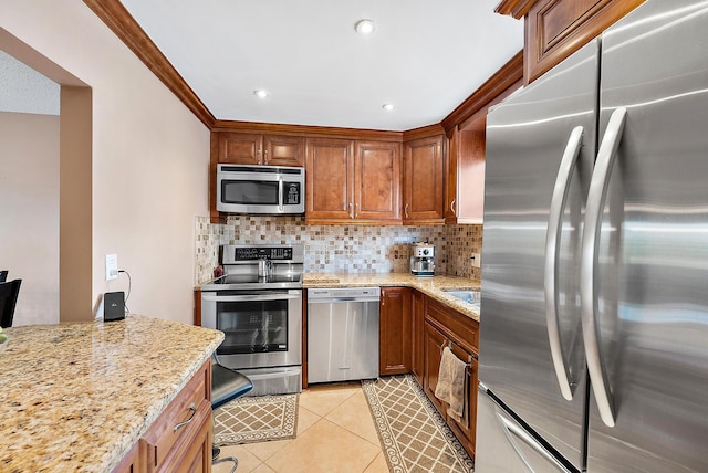 kitchen with appliances with stainless steel finishes, light stone counters, light tile patterned floors, and tasteful backsplash