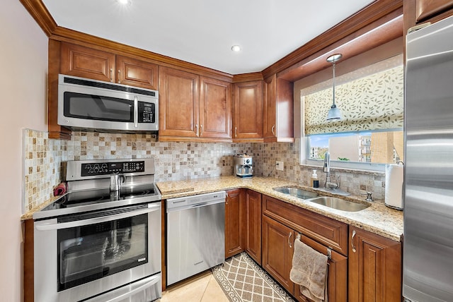 kitchen featuring tasteful backsplash, hanging light fixtures, stainless steel appliances, light stone countertops, and sink