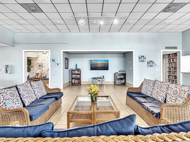 living room with a drop ceiling and light tile patterned floors