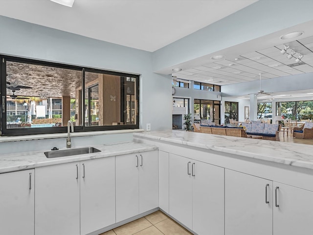 kitchen featuring white cabinets, light stone countertops, a wealth of natural light, and sink