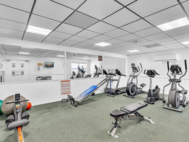 exercise room featuring a wall mounted air conditioner and a paneled ceiling