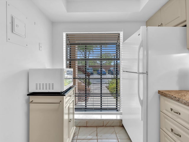 kitchen featuring white fridge, light tile patterned flooring, a wealth of natural light, and cream cabinets