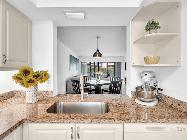 kitchen featuring light stone counters, white cabinetry, and hanging light fixtures