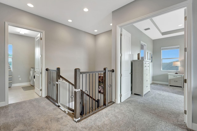 corridor with light carpet and washing machine and dryer