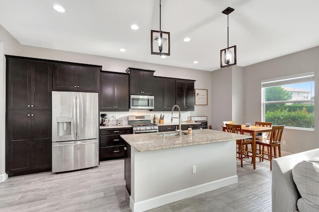 kitchen featuring appliances with stainless steel finishes, sink, pendant lighting, and light hardwood / wood-style floors