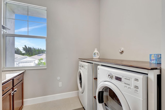 laundry room with cabinets, light tile patterned floors, a wealth of natural light, and washer and dryer