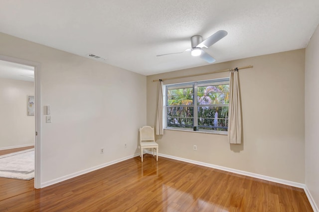 unfurnished room featuring ceiling fan, wood-type flooring, and a textured ceiling