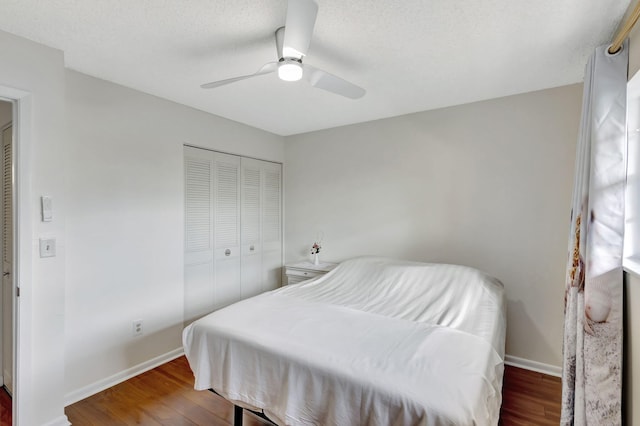 bedroom with ceiling fan, a textured ceiling, dark hardwood / wood-style floors, and a closet