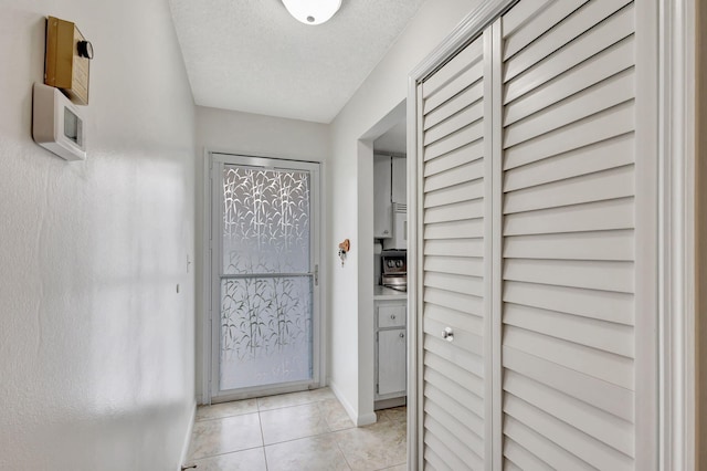 doorway featuring light tile patterned floors and a textured ceiling