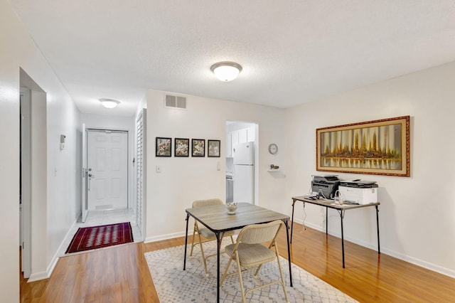 dining area with a textured ceiling and light hardwood / wood-style floors