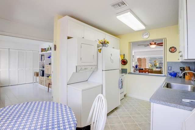 13735 Flora Pl Unit C, Delray Beach, FL 33484 - kitchen featuring a sink, stacked washer / drying machine, white cabinets, and a ceiling fan