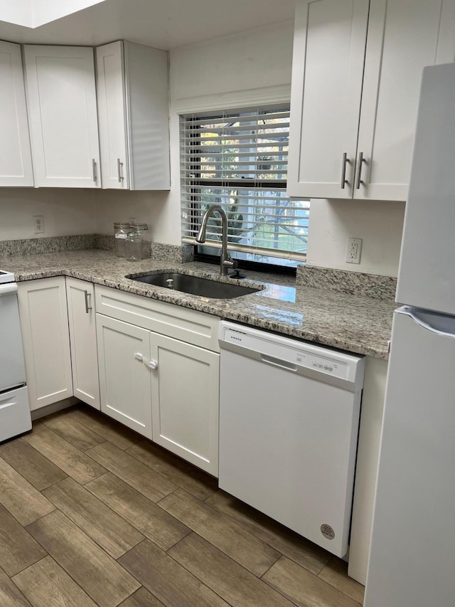 kitchen with light stone countertops, sink, dark wood-type flooring, white appliances, and white cabinets