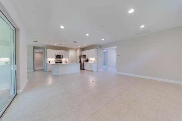 unfurnished living room featuring light tile patterned floors and sink