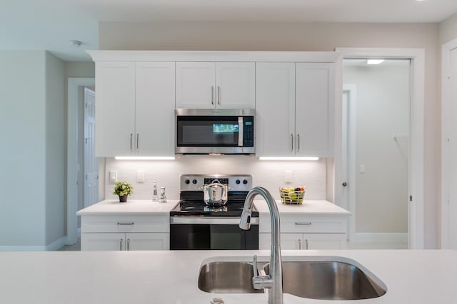 kitchen featuring stainless steel appliances, white cabinets, sink, and backsplash