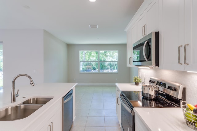 kitchen with sink, light tile patterned floors, backsplash, white cabinetry, and appliances with stainless steel finishes